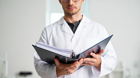 Врач-психиатр держит папку, стоя в коридоре